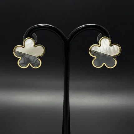 Close-up of flower-shaped stud earrings with half white and half grey shell inlay in gold setting studs.